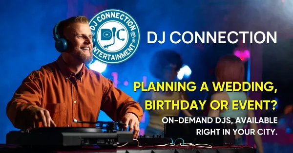 A DJ wearing headphones and an orange shirt operating a turntable at an event with a dance floor and blue lighting in the background.