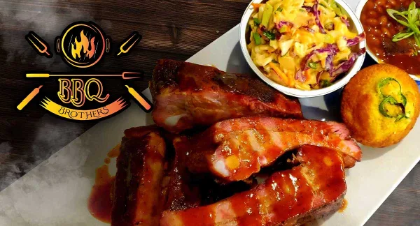 A BBQ Brothers Cafe platter featuring smoked ribs, brisket, coleslaw, and a jalapeno cornbread muffin.