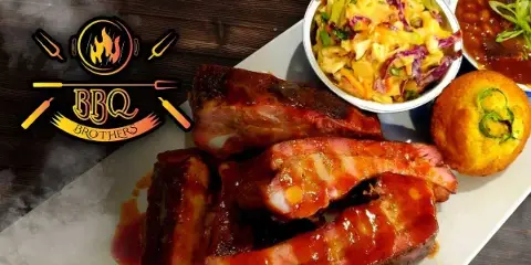 A BBQ Brothers Cafe platter featuring smoked ribs, brisket, coleslaw, and a jalapeno cornbread muffin.