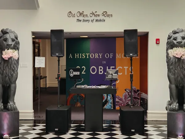 Professional DJ booth with turntables, mixer, and speakers set up at an event venue.
