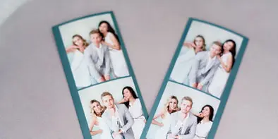 A printed photo booth strip showing a wedding couple with a customized digital overlay.