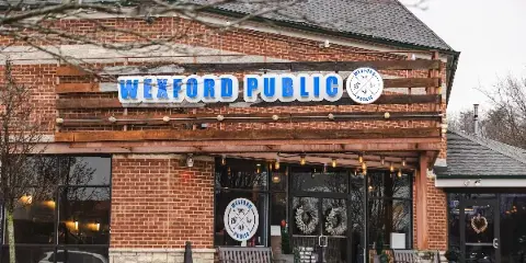 Exterior view of the Wexford Public restaurant building featuring a brick facade and prominent blue signage.