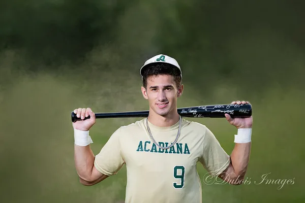 A young man in an Acadiana baseball uniform holding a signed bat, with a Dubois Images watermark.