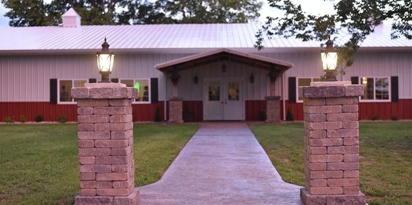 Exterior view of The Venue at Rocking V Ranch event center with brick pillars and a paved walkway leading to the entrance.