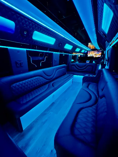 Interior of a luxury party bus with wrap-around leather seating and blue LED lighting