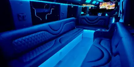 Interior of a luxury party bus with wrap-around leather seating and blue LED lighting