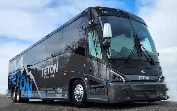 A black Teton Stage Lines charter bus parked outdoors.