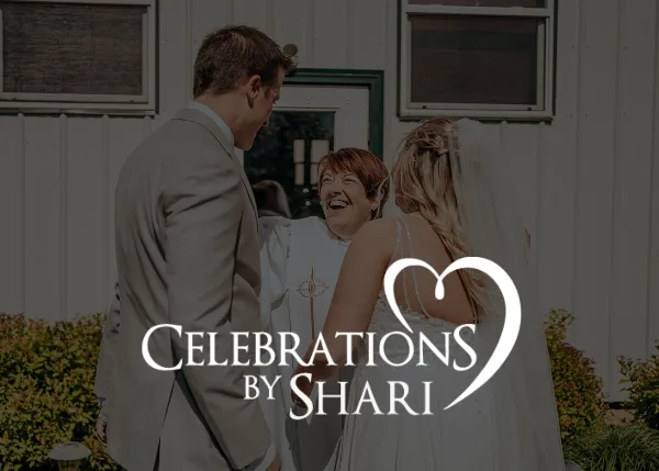 A wedding officiant in white robes smiling while standing between a bride and groom during a ceremony.