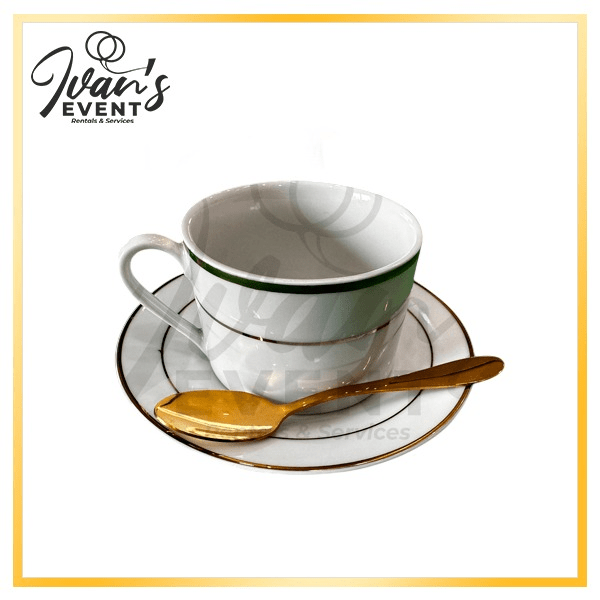 A white coffee cup with a green rim, saucer, and gold spoon set on a white background.