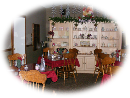 Interior view of a restaurant dining room featuring tables with red tablecloths, wooden chairs, and a large display cabinet filled with china.