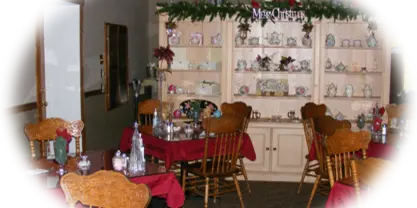Interior view of a restaurant dining room featuring tables with red tablecloths, wooden chairs, and a large display cabinet filled with china.