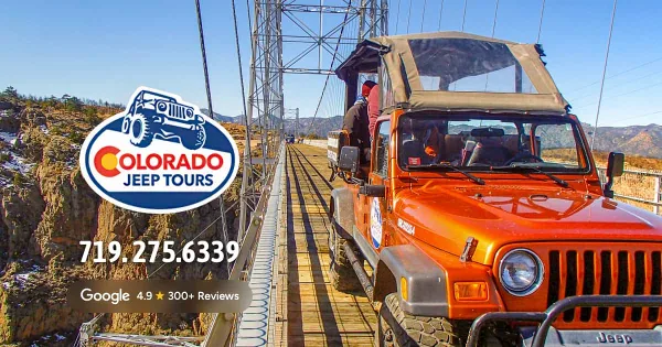 An orange Jeep parked on the Royal Gorge Bridge with a scenic canyon view in the background.