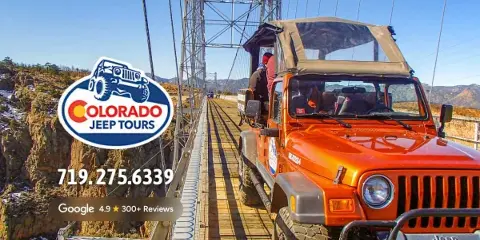 An orange Jeep parked on the Royal Gorge Bridge with a scenic canyon view in the background.