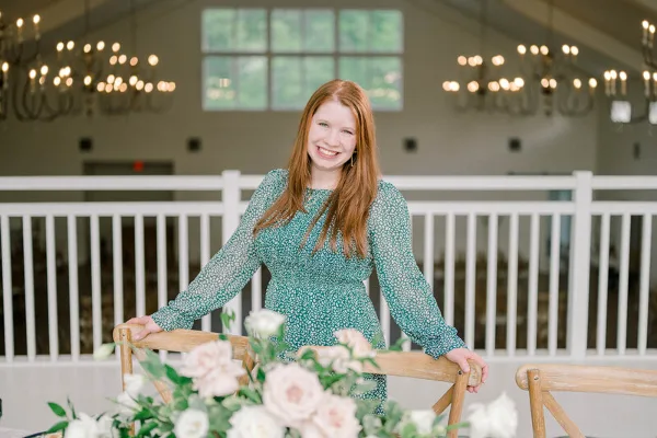 Kaitie Gill standing in a wedding venue with a floral tablescape