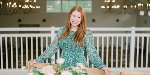 Kaitie Gill standing in a wedding venue with a floral tablescape