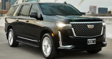 A black luxury SUV parked on a bridge with a city skyline in the background.