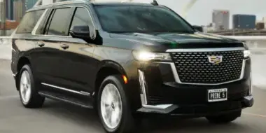 A black luxury SUV parked on a bridge with a city skyline in the background.