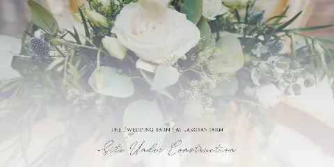 A close-up photograph of a wedding floral arrangement featuring white roses, eucalyptus leaves, and thistle flowers.