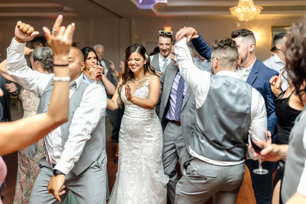 A bride and wedding guests dancing on a dance floor at a reception.