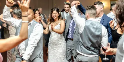 A bride and wedding guests dancing on a dance floor at a reception.