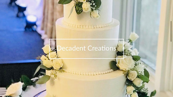A three-tier white wedding cake decorated with fresh white roses and greenery.