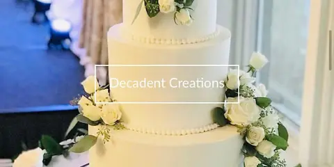 A three-tier white wedding cake decorated with fresh white roses and greenery.