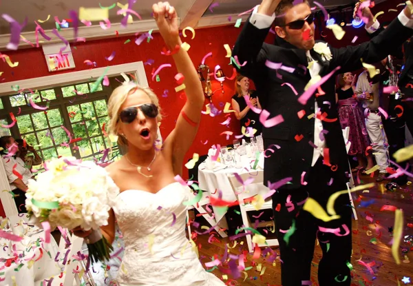 A bride and groom dancing at a wedding reception with confetti falling around them.