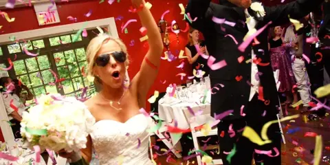 A bride and groom dancing at a wedding reception with confetti falling around them.