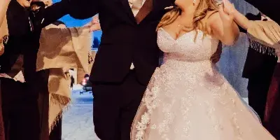 A bride and groom laughing and celebrating with sparklers at a wedding event.