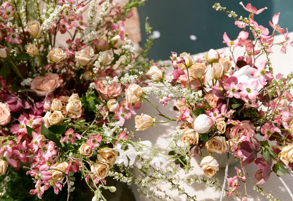 Close-up of a lush floral arrangement with pink clematis, cream roses, and white filler flowers.