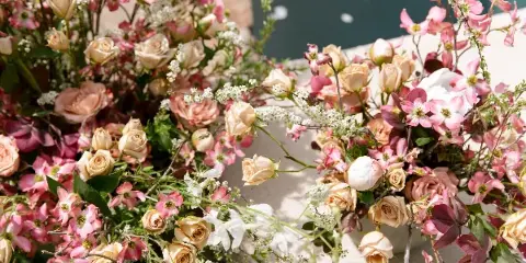 Close-up of a lush floral arrangement with pink clematis, cream roses, and white filler flowers.