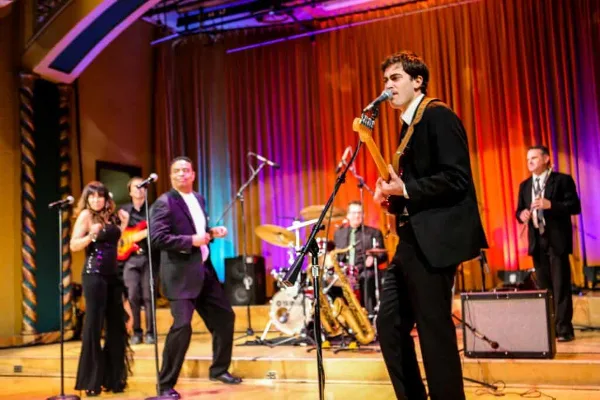 A live band performing on a stage with a singer, guitarist, and other musicians.