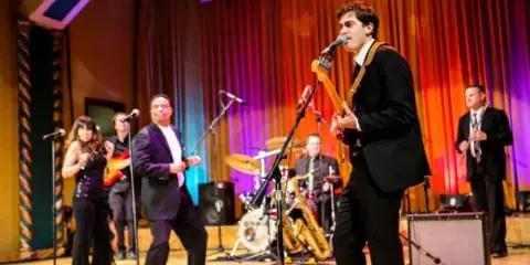 A live band performing on a stage with a singer, guitarist, and other musicians.