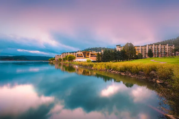 Exterior view of the Inn of the Mountain Gods resort building and casino complex situated on the edge of a lake at dusk.