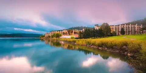 Exterior view of the Inn of the Mountain Gods resort building and casino complex situated on the edge of a lake at dusk.