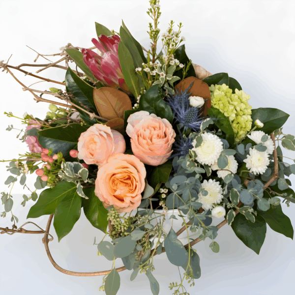 A mixed floral arrangement featuring peach roses, white chrysanthemums, green hydrangea, and eucalyptus foliage in a round container.