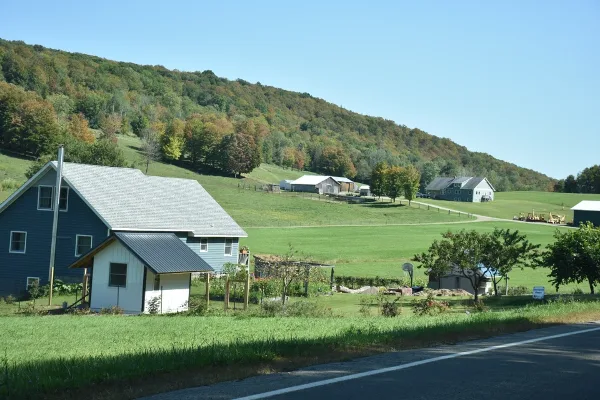 Rural landscape with a blue house and green fields near a road in Cattaraugus, NY