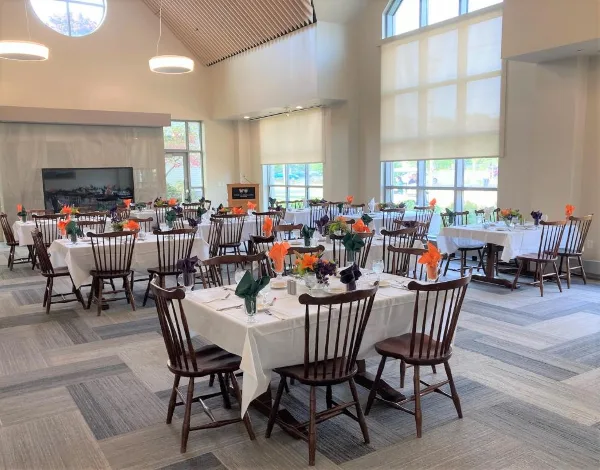 A spacious indoor wedding reception hall with high ceilings, large windows, and multiple tables set for a banquet.