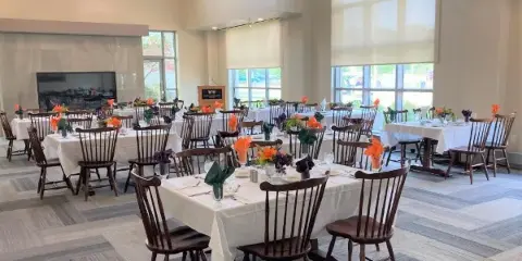 A spacious indoor wedding reception hall with high ceilings, large windows, and multiple tables set for a banquet.