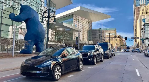 A fleet of black luxury sedans, SUVs, and vans parked along a city street in Denver, Colorado.