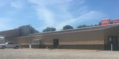 Exterior view of a commercial equipment rental center with a gravel lot and a pickup truck parked in front.