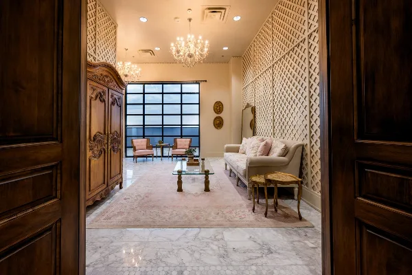 Elegant venue interior with chandeliers, marble floor, sofa, and large window overlooking a view.