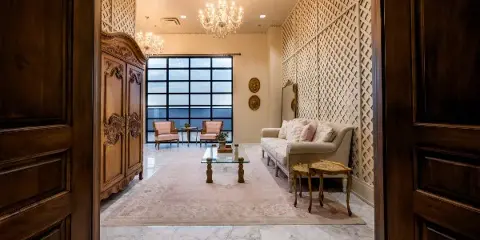 Elegant venue interior with chandeliers, marble floor, sofa, and large window overlooking a view.