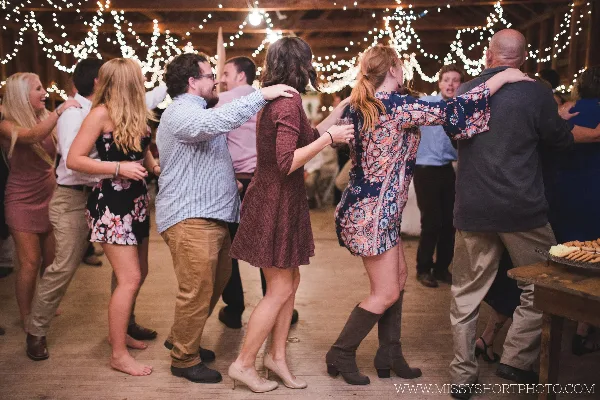 Guests dancing at a wedding reception under string lights.