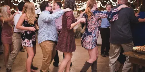 Guests dancing at a wedding reception under string lights.