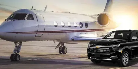 A black luxury SUV parked on a tarmac next to a private jet.