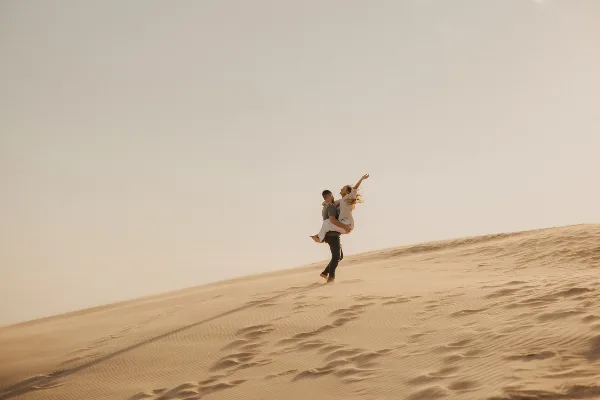 A couple posing on a sand dune in a professional wedding or elopement photograph.