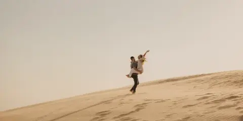 A couple posing on a sand dune in a professional wedding or elopement photograph.