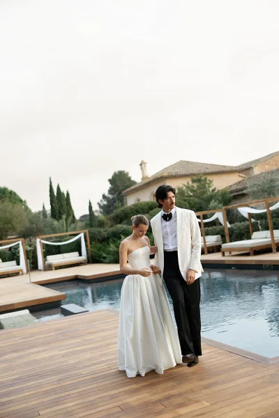 A bride and groom standing by a pool at a destination wedding venue.
