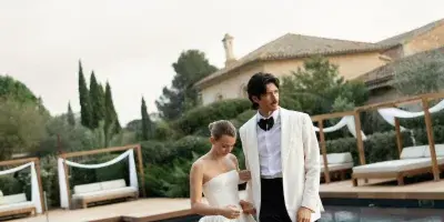 A bride and groom standing by a pool at a destination wedding venue.